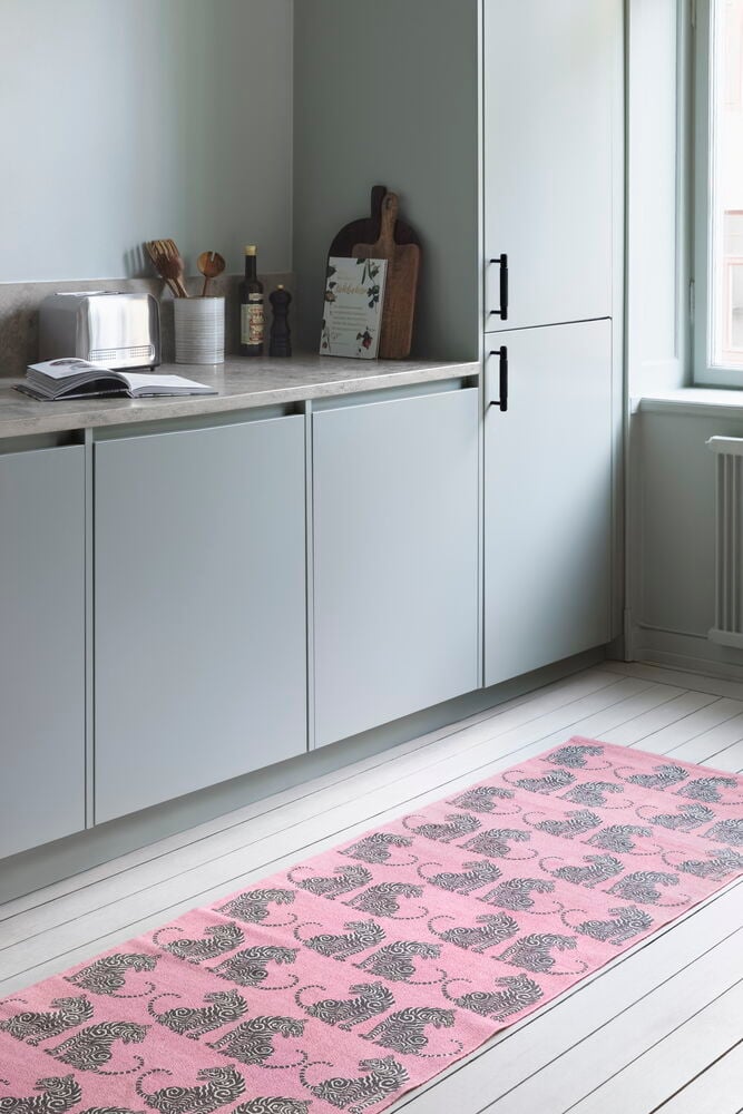 Rosérosa Bomull Gangteppe Tigris 70x200 cm med tigermønster, plassert på et hvitt tregulv i et kjøkken.