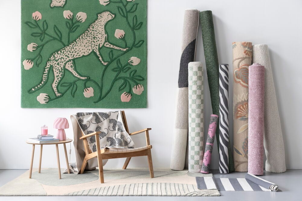 Ullmatta Cheetah 160x230 cm Grön Ull, visas med flera rullade och platta mattor, samt en stol.