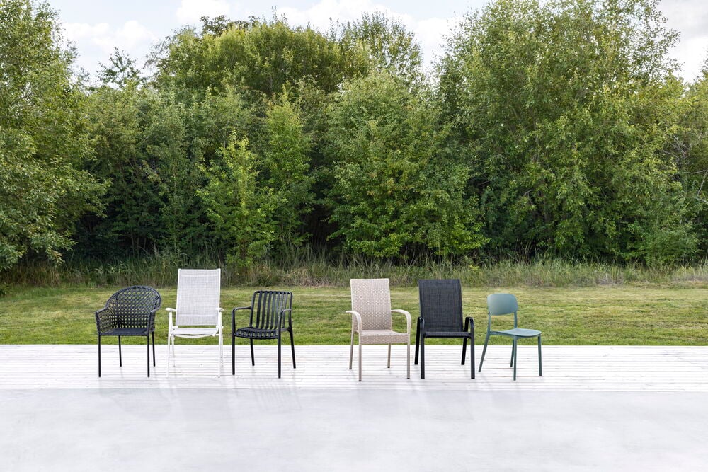 Beige Kunstrattan Stuhl Rimini und fünf weitere Gartenstühle werden auf einer weißen Terrasse gezeigt.
