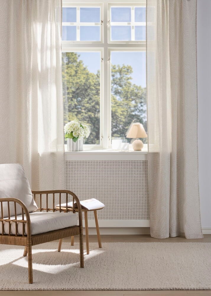 Naturfarbene Sophie Vorhänge Polyester 2er-Pack, transparent mit dezentem Muster, hängen an einem Fenster.