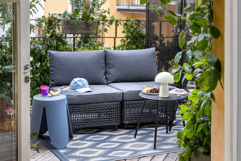Settbord Paris 2-pk Svart Stål, grå sofa, blå krakk, caps, hvit lampe, på blått teppe.