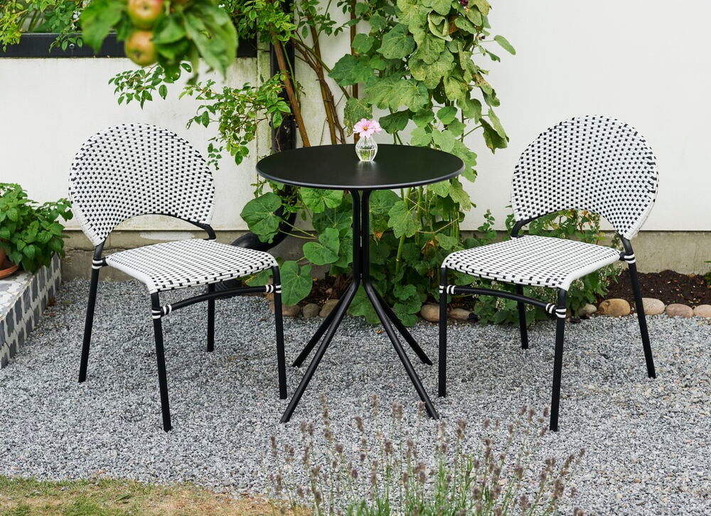 Kafébord Bistro Ø60 cm Svart Stål og to svart-hvite flettede stoler på en gruslagt uteplass.