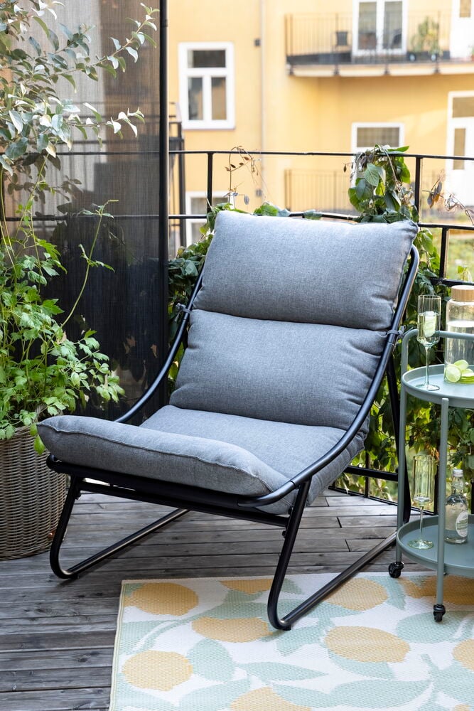 Svart och grå Relaxstol Bari, runt grönt sidobord och mönstrad utomhusmatta.