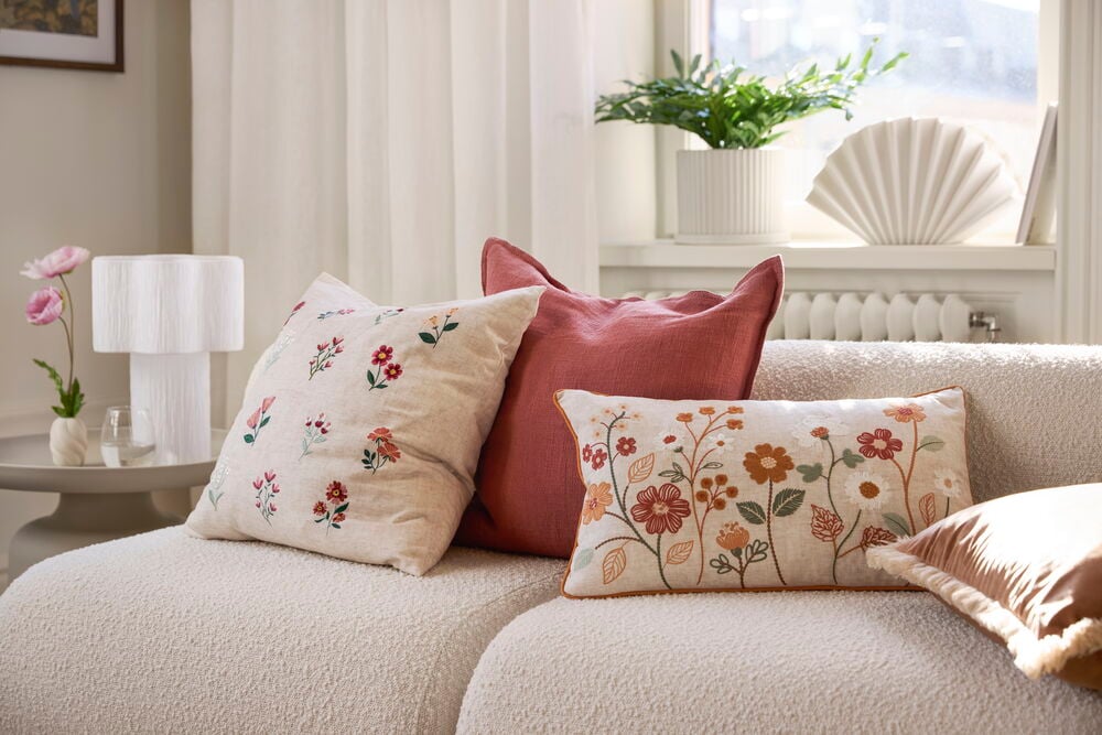 Prydnadskudde Florens Natur Polyester: beige med spridd blomsterbroderi, en rödrosa och en rektangulär blommig kudde.
