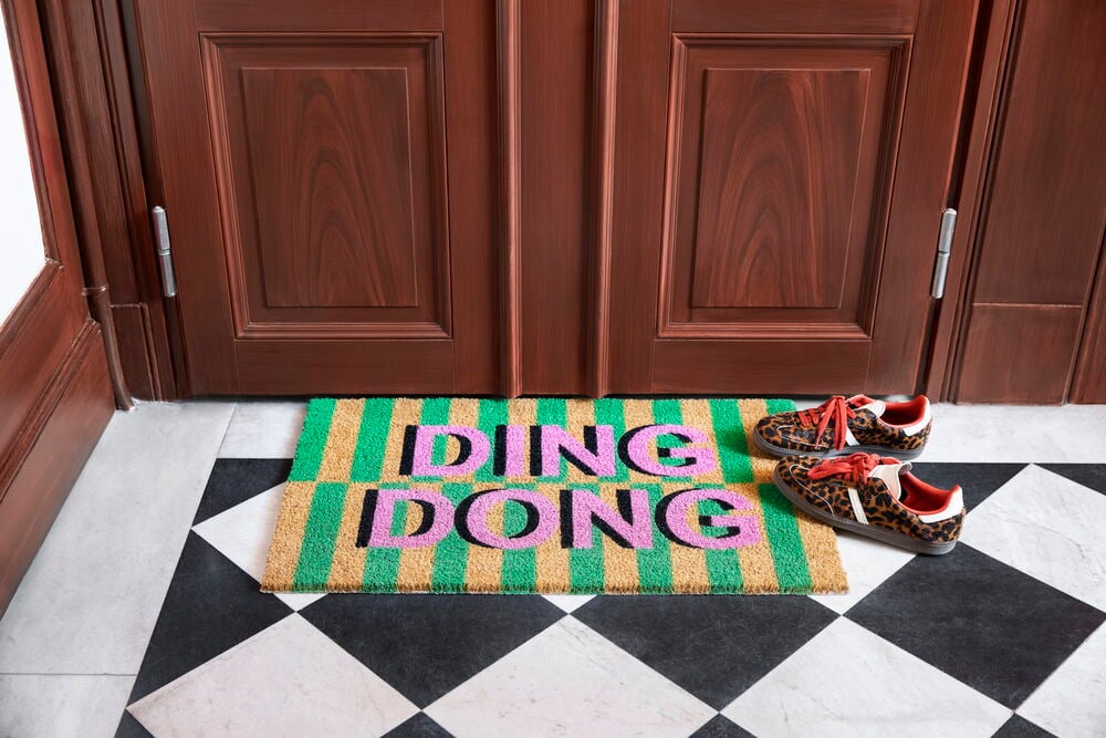 Fußmatte Ding Dong 45x75 cm in Pink und Grün Kokosfaser, mit einem Paar Sneaker mit Leopardenmuster.