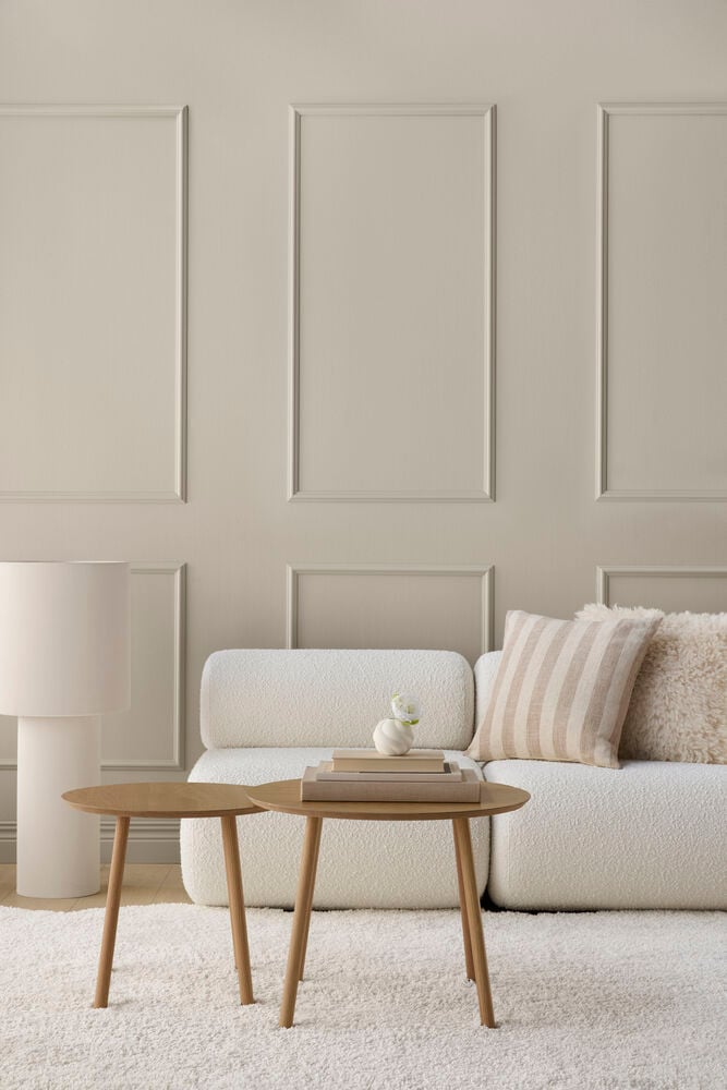 Off-white Golvlampa Porto 37x89 cm bredvid vit soffa, två träbord, kuddar och matta.