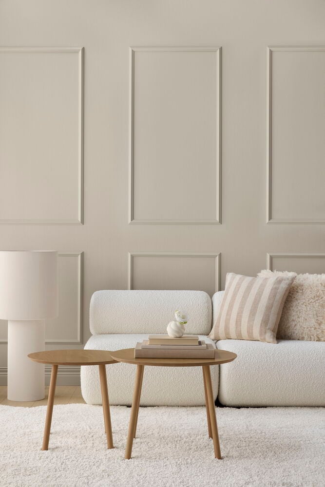 Fußbodenlampe Porto 37x89 cm Off-white, ein weißes Sofa mit Kissen und zwei runden Beistelltischen.