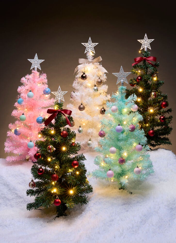 Hellrosa 60 cm PVC Weihnachtsbaum mit blauen Ornamenten und Lichtern, umgeben von vier anderen dekorierten Bäumen.