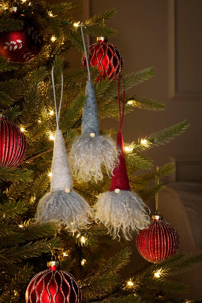Drei Weihnachtswichtel Noel mit grauen, beigen, roten Filzhüten, langen zotteligen Bärten und Holznasen an einem Baum.