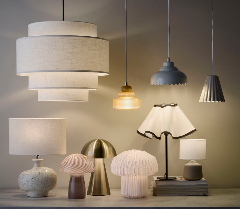 Lampfot Geneva 11x28 cm, en spräcklig vit keramikfot med tygskärm, bland många andra lampor.