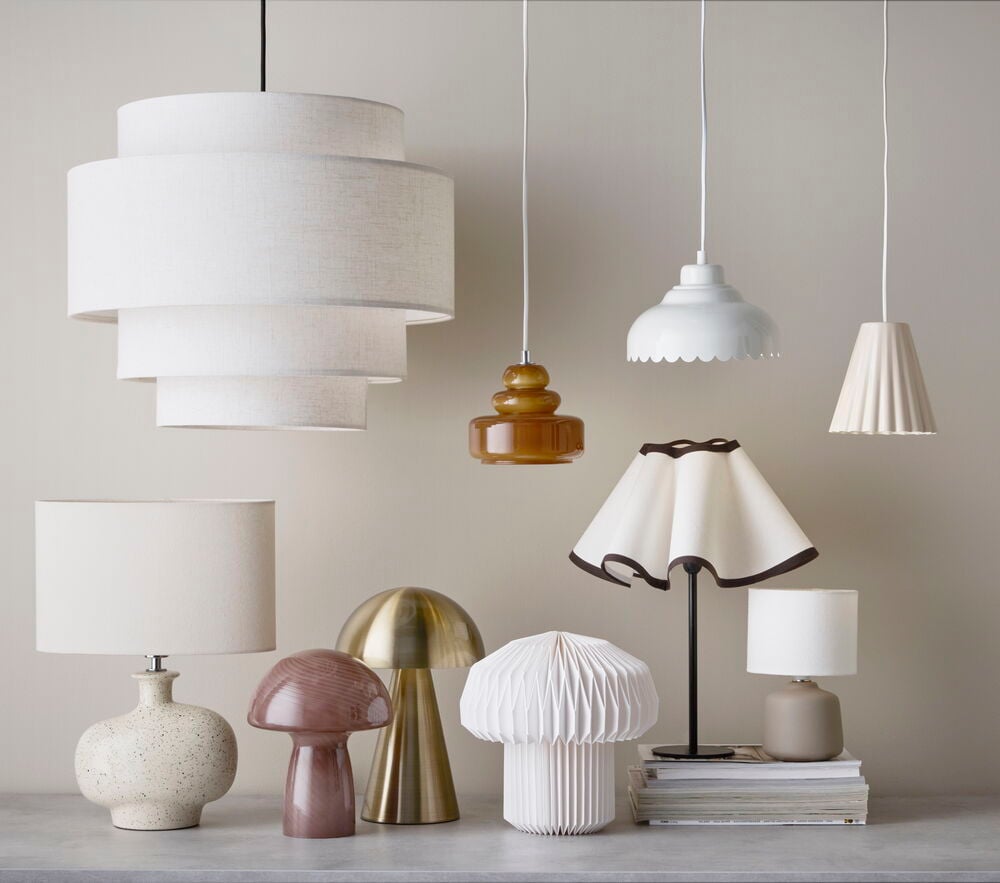 Bordslampa Porano beigefärgad bas, vit skärm; skiktade, bärnstensfärgade, vågiga, veckade taklampor; övriga bordslampor.