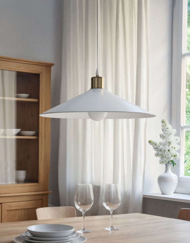 Vit taklampa med mässingsdetalj över matbord.