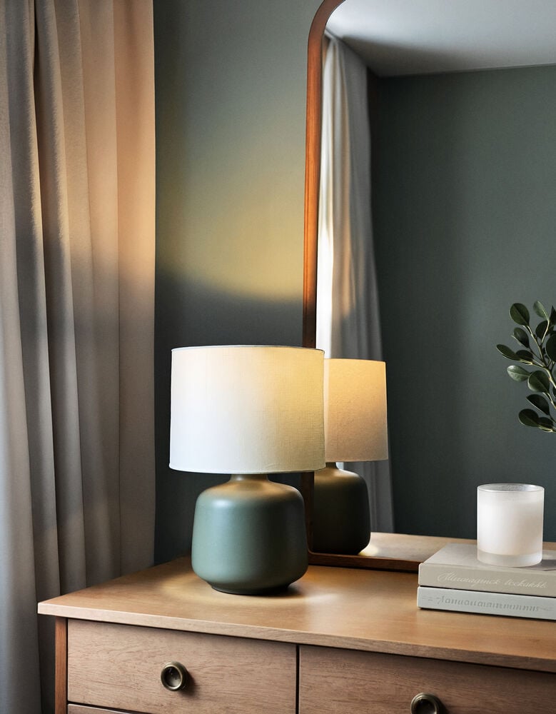 Klassisk bordslampa med vit skärm på träbyrå.