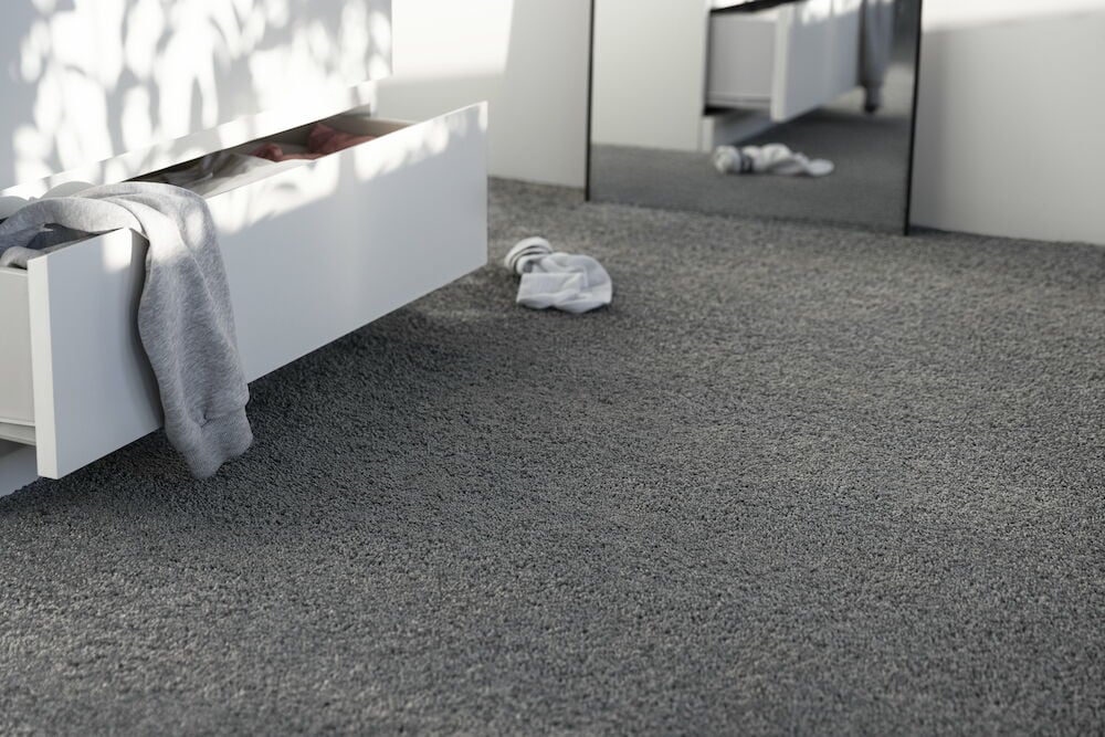 Tummanharmaa matto, jossa on lyhyt nukka makuuhuoneessa.