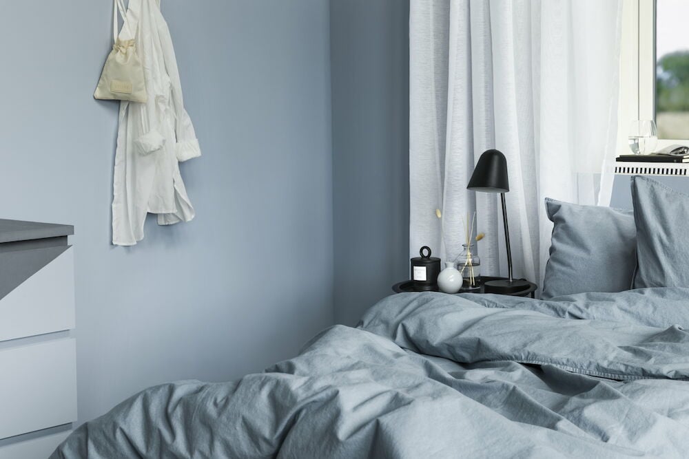 Sovrum med blå väggar och matchande sängkläder.