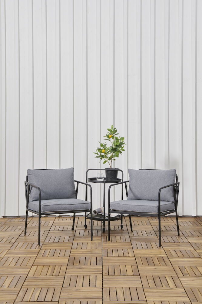 Kaksi harmaata nojatuolia, pöytä ja kasvi.