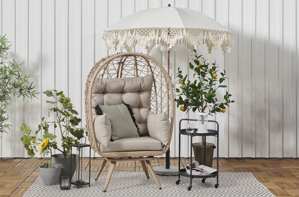 Valkoinen aurinkovarjo, jossa on koristeellisia tupsuja terassille.