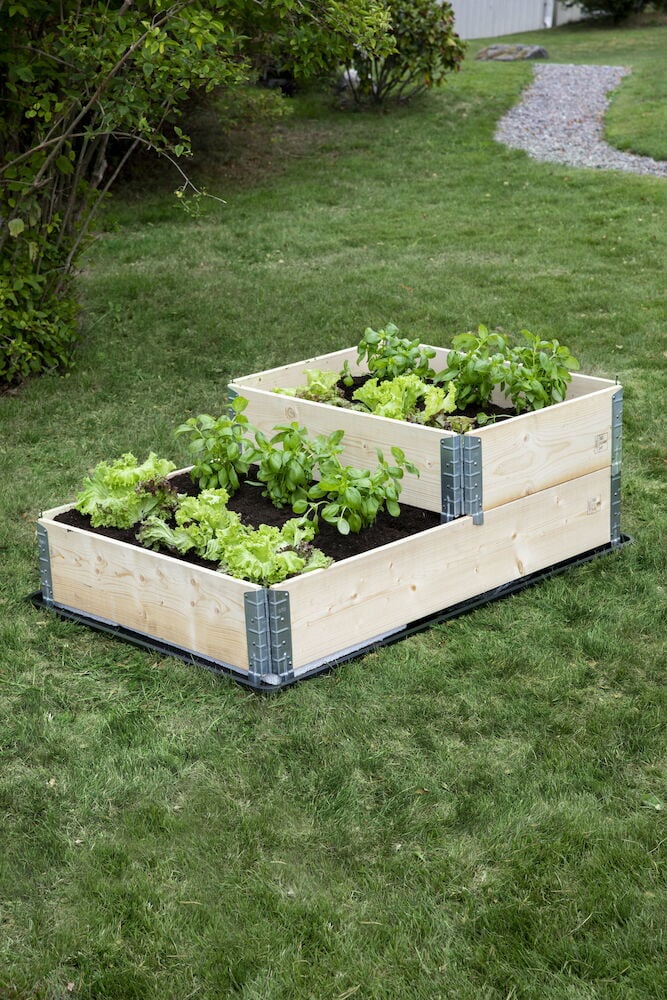 Två staplade odlingslådor i trä med grönsaker.