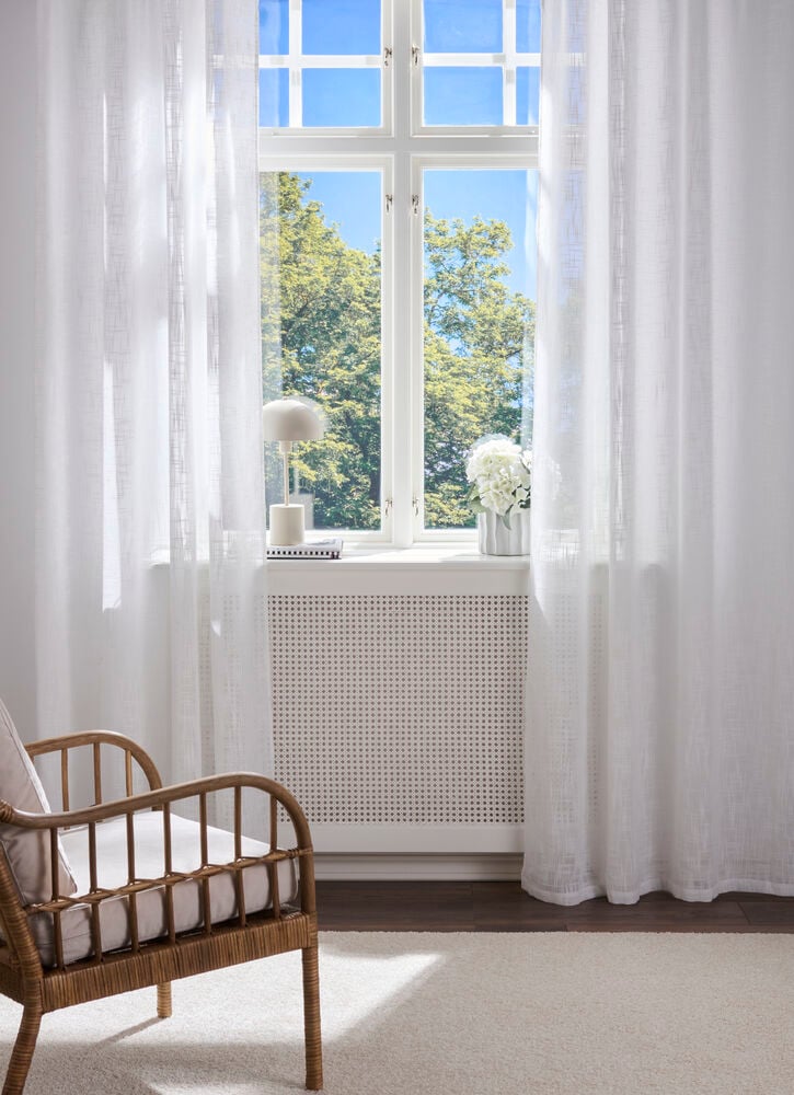 Gardinlengder Lina 140x250 cm Hvit Polyester 2-pakning henger på et solfylt vindu.