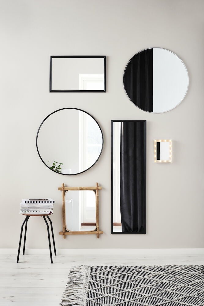 Rektangulär svart spegel på ljus vägg.
