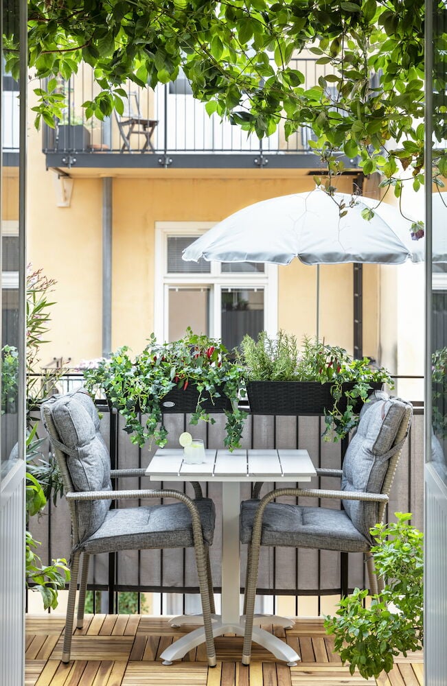 Musta suorakulmainen kukkalaatikko, jossa on vihreitä kasveja parvekkeella.