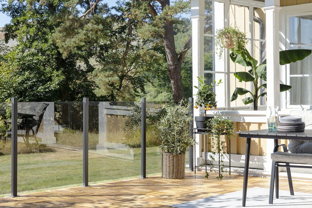 Glasgeländer mit rauchgrauem Glas auf sonniger Terrasse.