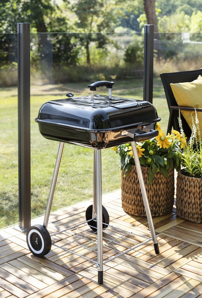 Liten svart kolgrill med lock på uteplats.