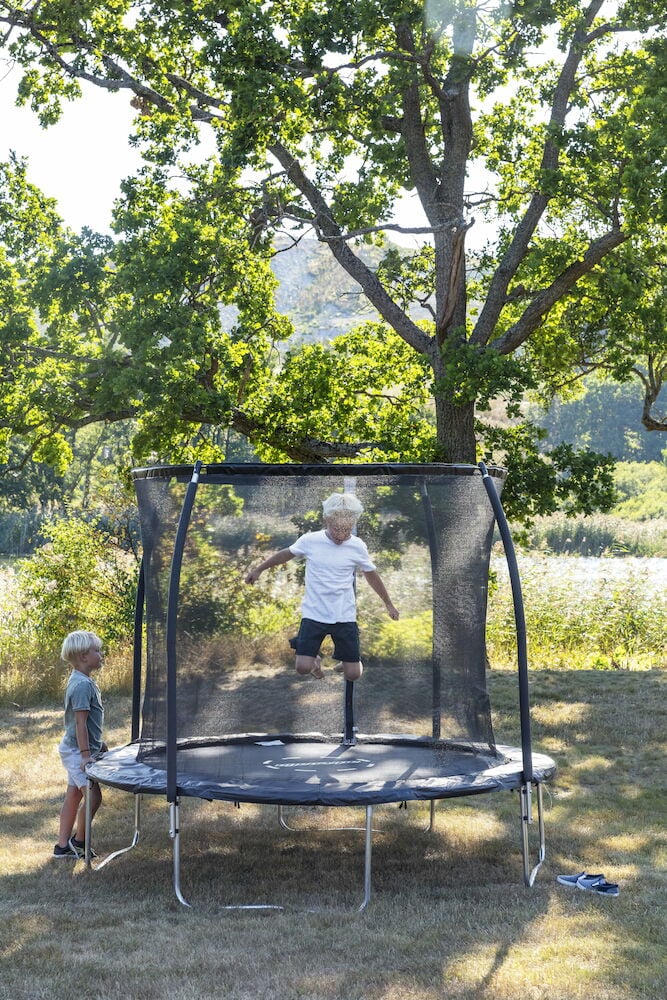 To barn ved trampoline med sikkerhetsnett utendørs.