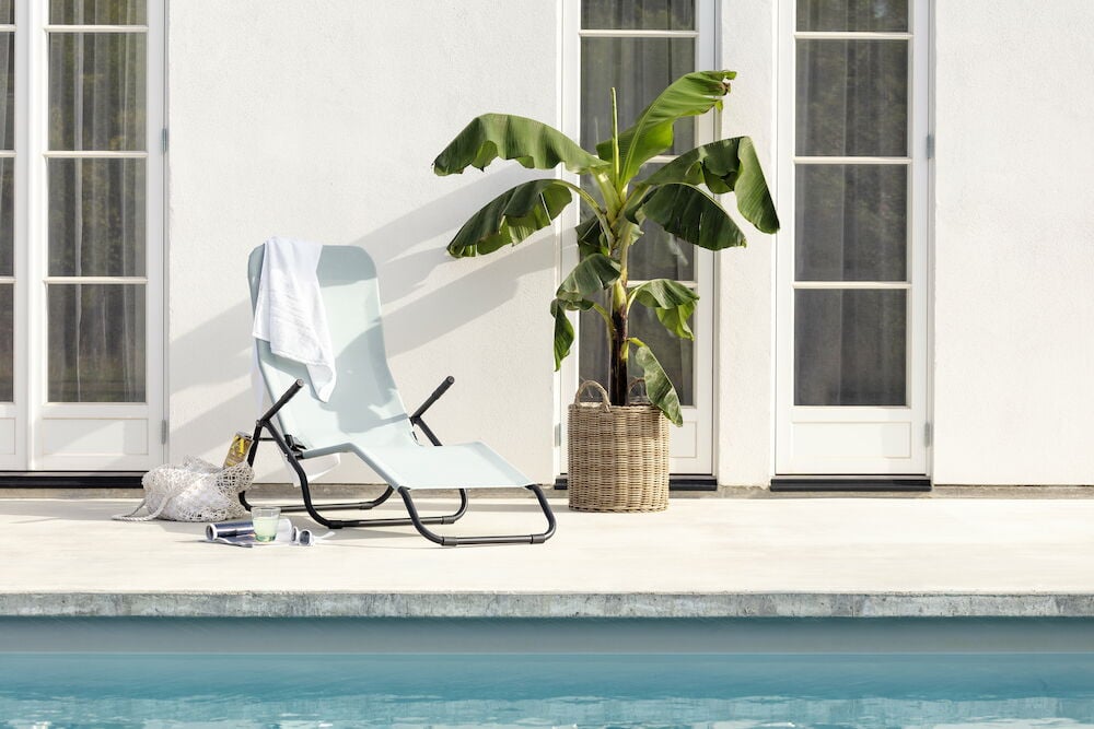 Brun kruka med grön växt utomhus vid pool.