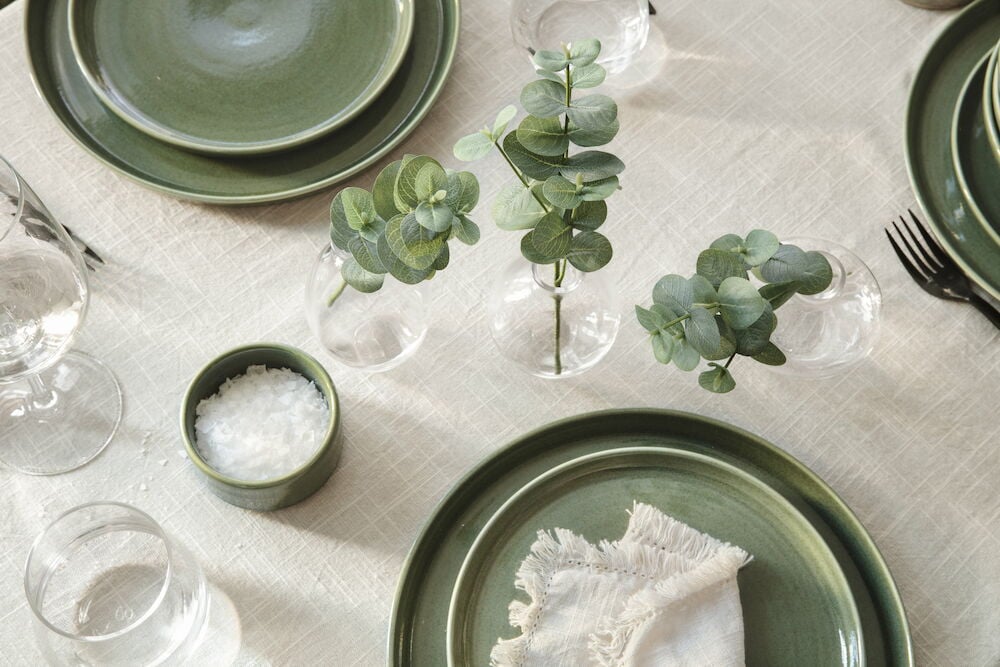 Vihreä eukalyptus pienissä maljakoissa katetulla pöydällä.