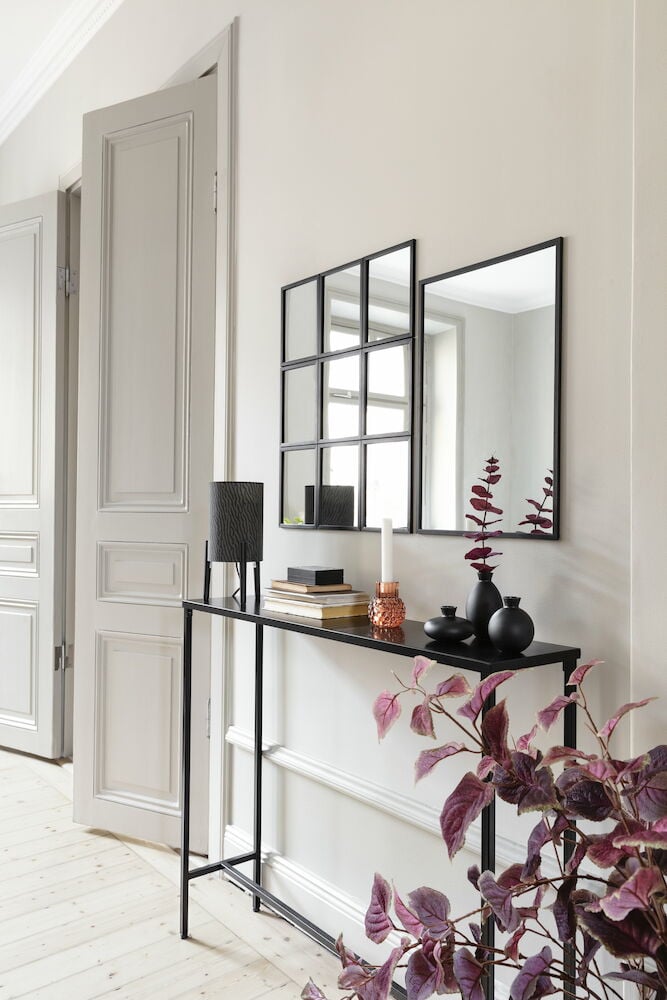 Smalt svart avlastningsbord med dekorationer och speglar.