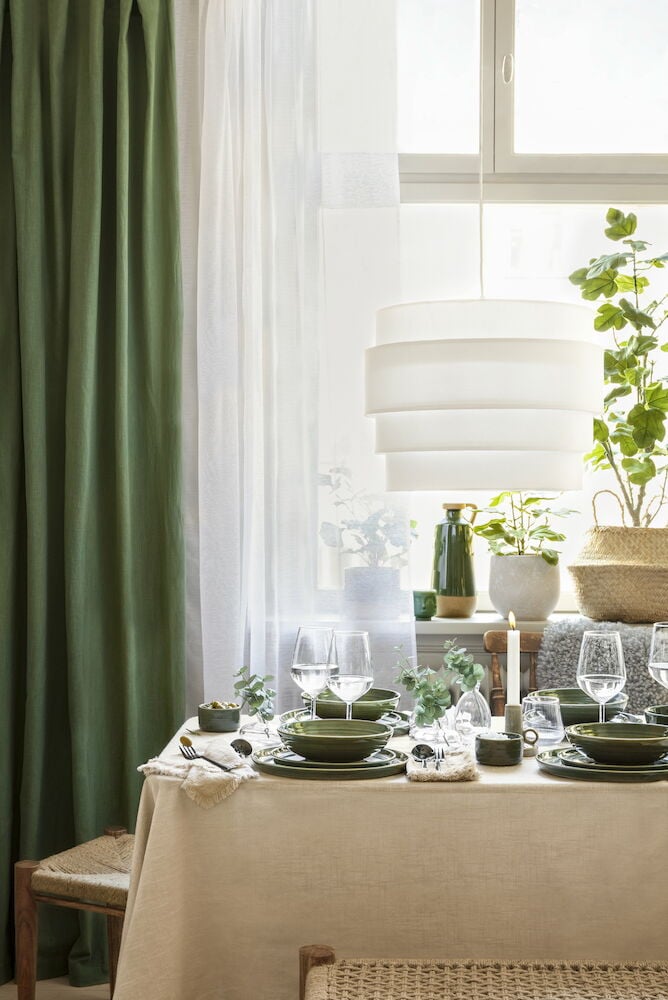 Vihreät puuvillaverhot katetun pöydän äärellä.