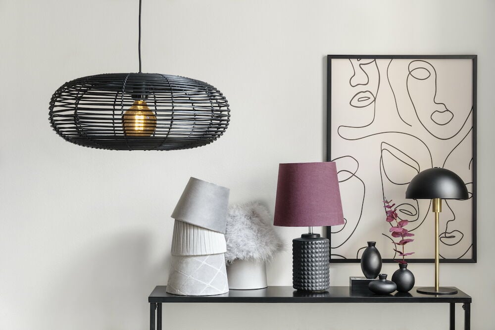 Schwarzer Metalltisch mit Lampen und Bild im Hintergrund.