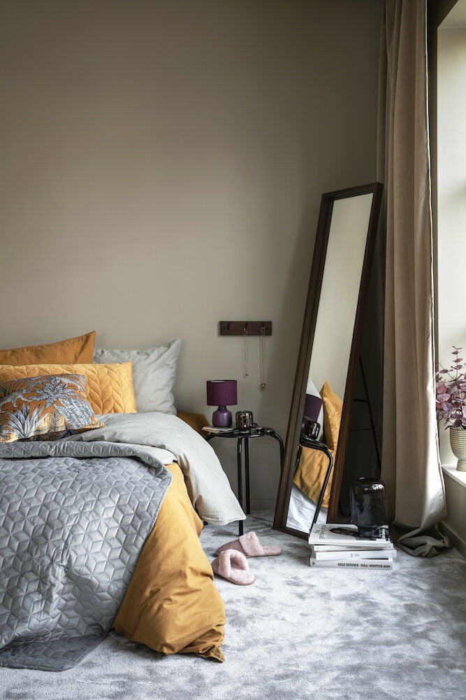 Vaalea samettiverho purjerenkailla ikkunassa.