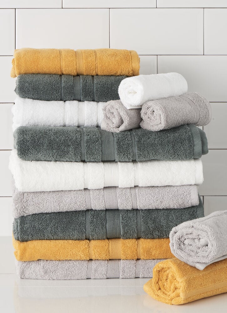 Vikta handdukar i vitt, grått och gult.