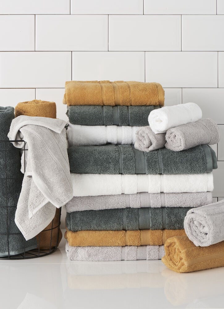 Flera badhanddukar i grått vitt och gult staplade.