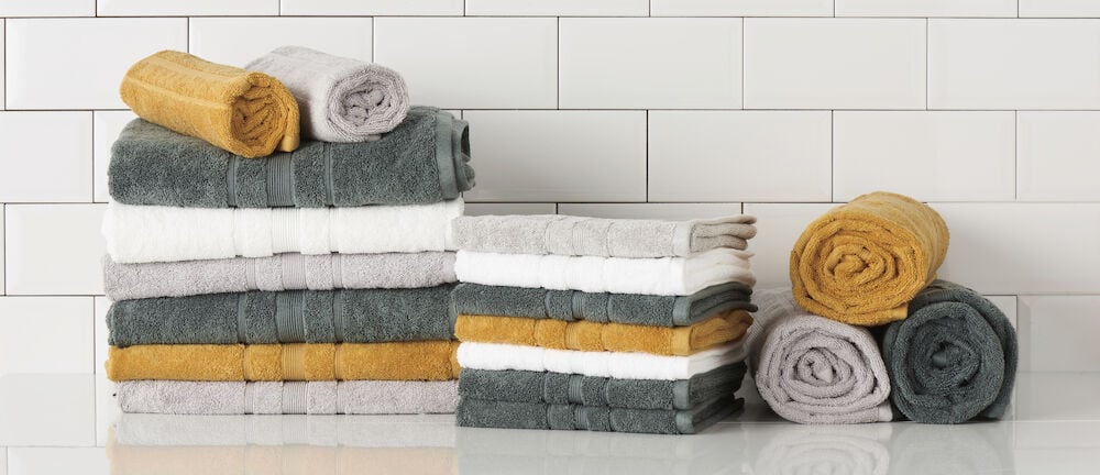 Vikta och rullade handdukar i vitt, grått, gult.