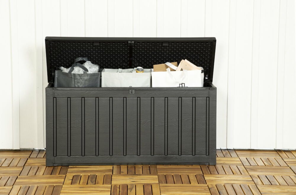 Musta muovinen säilytyslaatikko, jossa on avoin kansi.