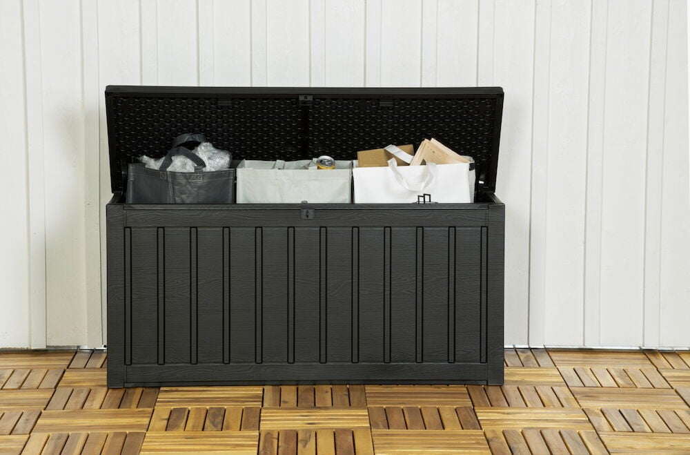 Musta muovilaatikko, jossa on avoin kansi ja säilytettyjä tavaroita.