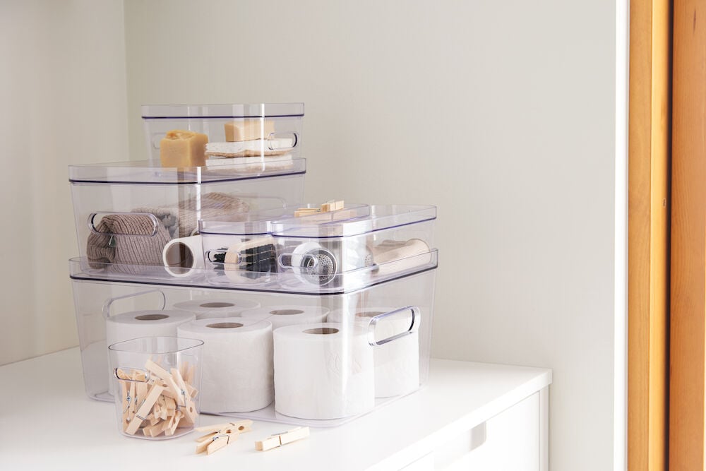 Flera transparenta förvaringslådor staplade med olika innehåll.