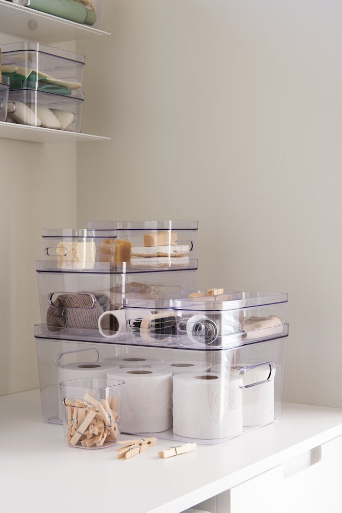 Flera transparenta förvaringslådor staplade med olika innehåll.