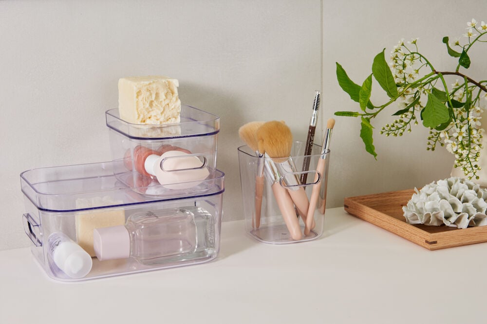 Transparent förvaringslåda med smink och tvål på hylla.