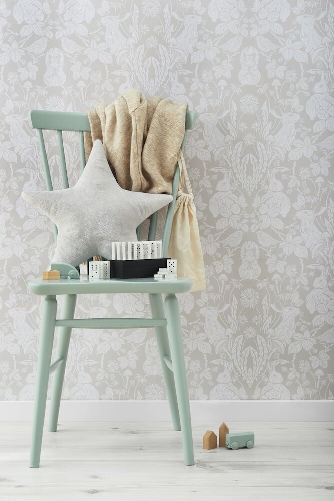 Vihreä tuoli tyynyllä, peitolla ja leluilla.