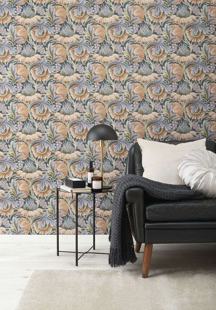 Orange blomstertapet bakom svart soffa och sidobord.