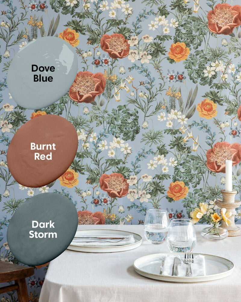 Vaaleansininen kukallinen tapetti katetun pöydän takana.