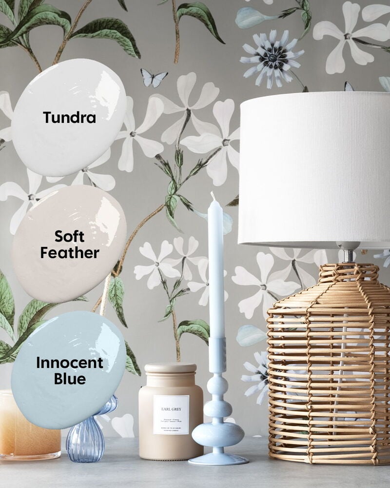 Grå blommig tapet med fjärilar bakom bordslampa.