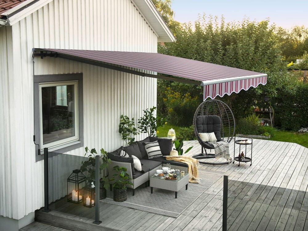 Grå och bordeaux terrassmarkis över uteplats med möbler.