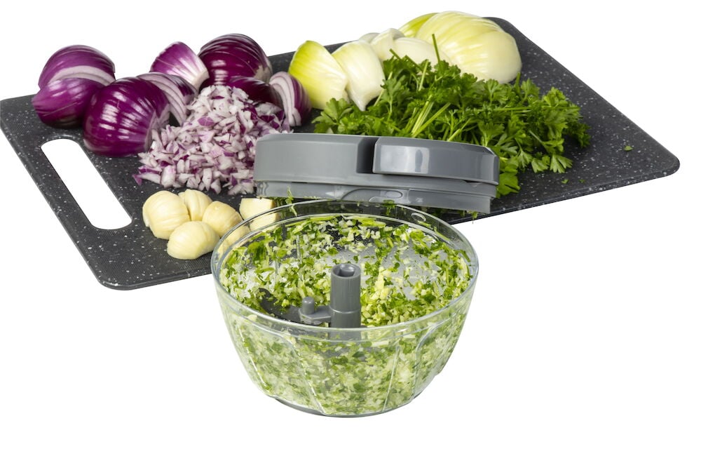 Manuell minihackare med hackade örter och lök.