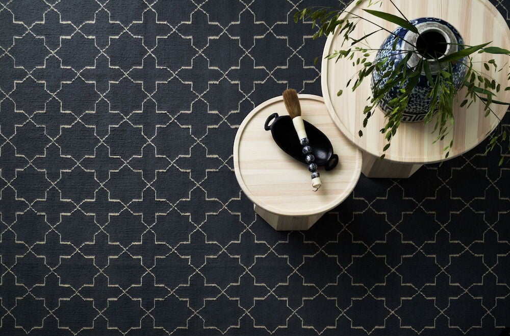 Käsinkudottu tummansininen villamatto geometrisella kuviolla.