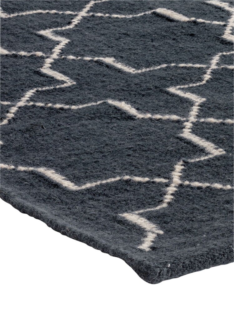 Tummansininen käsin kudottu villamatto, jossa valkoinen siksak-kuvio.